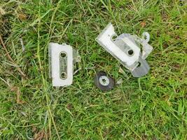 broken tape cassette in the grass flat view photo