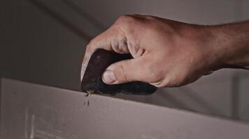 Processing the edges of a sink blank in a plumbing workshop. Close-up, hands of a working man with a scraper. video