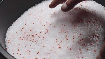 A woman mixes plastic granules with orange pigment to create colored plastic. Polymer composites are used in industry as raw materials for the production of various products video