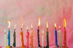 A row of candles with different colors and sizes, some of which are lit photo