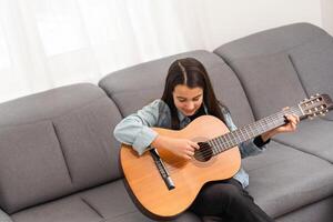 beautiful young girl plays guitar at home photo