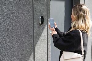 hembra entrando secreto llave código para consiguiendo acceso y paso edificio utilizando solicitud en móvil teléfono, mujer prensado botones en controlar panel para encantador inteligente hogar sistema foto