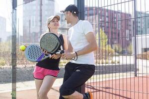 retrato de dos sonriente deportista posando en padel Corte al aire libre con raquetas - padel jugadores foto