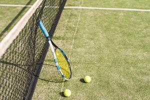 Tennis racquet and tennis balls at the net on the lines on a tennis court. photo