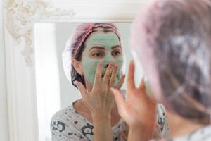 Self care. a woman applying clay mask to her face photo