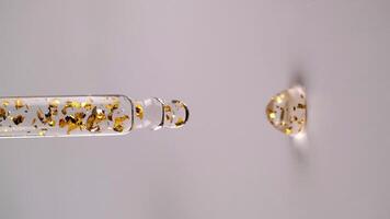 líquido gel ou sérum com ouro partículas pinga a partir de uma pipeta, vertical formatar. lento movimento. video