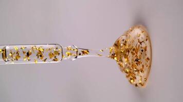 Liquid gel or serum with gold particles flows out of the pipette, vertical format. Slow motion. video