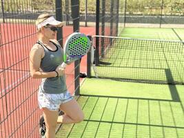 Ukraine Kyiv, May 03 2024. Portrait of smiling woman with padel tennis racket head at court photo