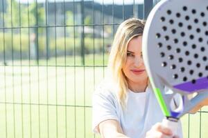 Happy female paddle tennis player during practice on outdoor court looking at camera. Copy space. photo