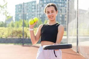 Adolescente niña participación padel raqueta en mano y Listo a regreso pelota mientras jugando en corte. foto