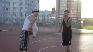 Two guy play basketball at district sports ground. video