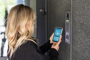 Smiling woman setting home security system with help of mobile application. photo