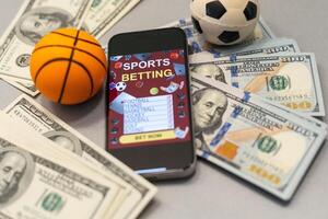 Smartphone with gambling mobile application and basketball ball with money close-up. Sport and betting concept photo