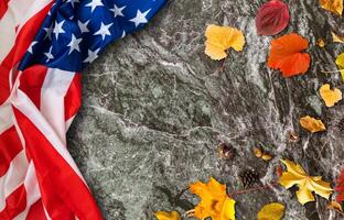 USA flag buried in yellow dry leaves. Autumn texture photo