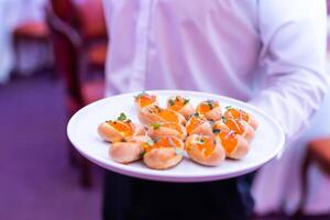 appetizers with caviar on plate at waiter hands inside party event photo