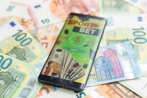 Sports betting website in a mobile phone screen, money photo