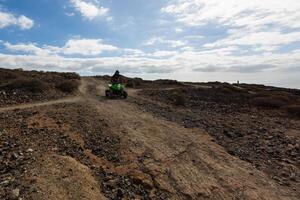 A man riding ATV in sand in protective helmet photo