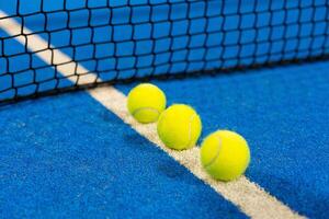 balls near the net of a blue padel tennis court photo