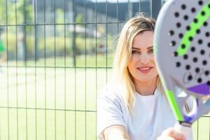 Ukraine Kyiv, May 03 2024. Portrait of smiling woman with padel tennis racket head at court photo