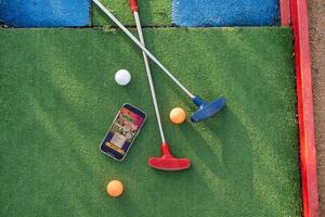 golf equipo en el verde césped. mini golf Deportes apuesta en un teléfono inteligente foto