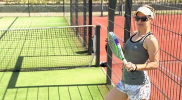 Happy female paddle tennis player during practice on outdoor court. Copy space. photo