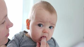 Mum cleaning baby teeth with a finger or toother, healthcare concept video