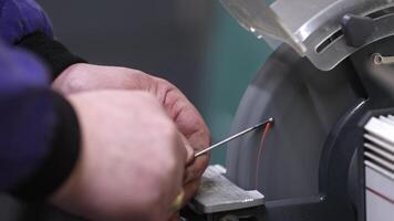 Man grinding small pieces of metal on the grind machine, industrial concept video