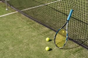 Tennis racquet and tennis balls at the net on the lines on a tennis court. photo