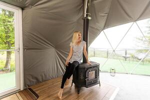 Young woman Rest in the mountains in Glamping. Cozy fireplace in a mountain house photo