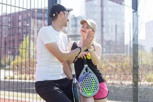 Ukraine Kyiv, April 02 2024. Young woman and man talking to each other after playing padel, walking along the net together photo