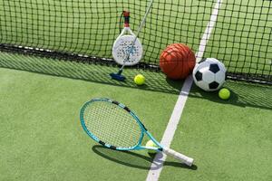 A variety of sports equipment including an american football, a soccer ball, a tennis racket, a tennis ball, and a basketball photo