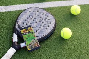 A tennis ball, a racket and a mobile phone with a put screen lie on a blue background. The concept of advertising a tennis club or ordering services. Horizontal photo