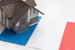 House model near France flag. Real estate sale and purchase concept. Space for text. photo