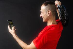 man holding paddel racket and smartphone with bet black background photo