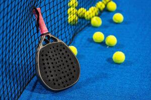 several balls by the net on a blue paddle tennis court photo