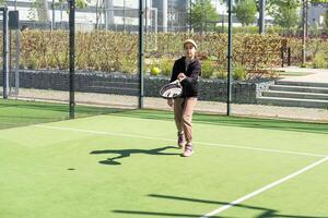 pequeño niña jugando padel y golpear el pelota con su raqueta al aire libre Deportes conceptos foto