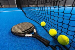 balls near the net of a blue padel tennis court photo