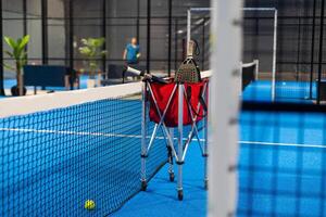 Paddle tennis rackets, balls and basket in court still life photo