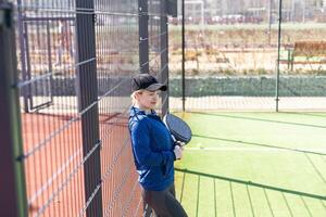 One woman with racquet and ball behind the net in paddle tennis court ready for training photo