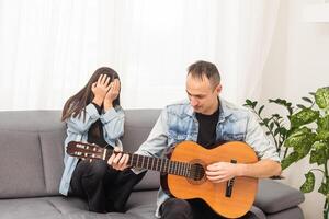 un padre enseñando su hija cómo a jugar guitarra. foto