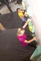 Young female mountaineer climbing artificial rock wall photo