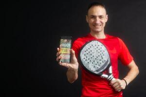 man holding paddel racket and smartphone with bet black background photo