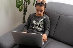 Teen girl school pupil studying online from home making notes. Teenage student distance learning on laptop doing homework, watching listening lesson. Remote education concept photo