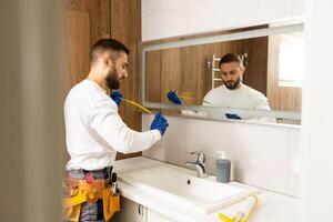 el trabajador instala el espejo en el baño. foto