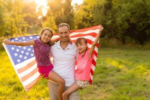 Happy family with the American flag in a wheat field at sunset. Independence Day, 4th of July. photo