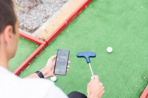 toque pantalla en mano, tableta en golf club. teléfono inteligente con un Deportes apuesta solicitud foto