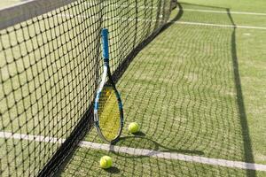 Tennis racquet and tennis balls at the net on the lines on a tennis court. photo