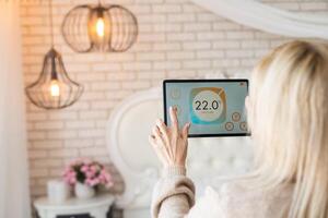 Young woman controlling home light with a digital tablet in the living room. Concept of a smart home and light control with mobile devices. photo