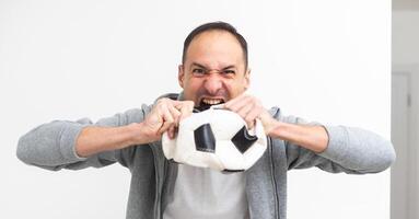 Joyful happy young man in shirt posing background. People sincere emotions lifestyle concept. Mock up copy space. Holding soccer ball doing winner gesture screaming photo