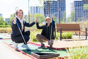 pequeño niña y madre jugando mini golf foto